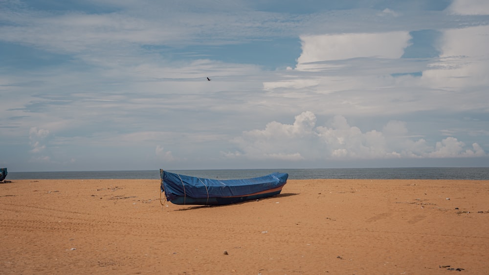 a blue boat sitting on top of a sandy beach