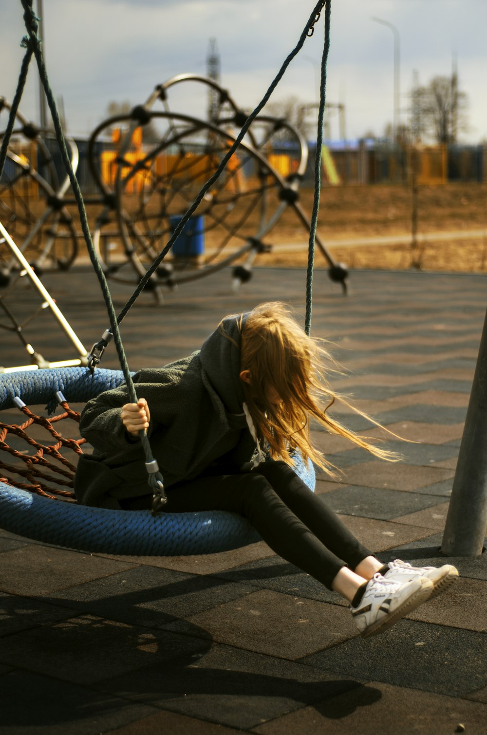 a little girl laying on a swing in a playground