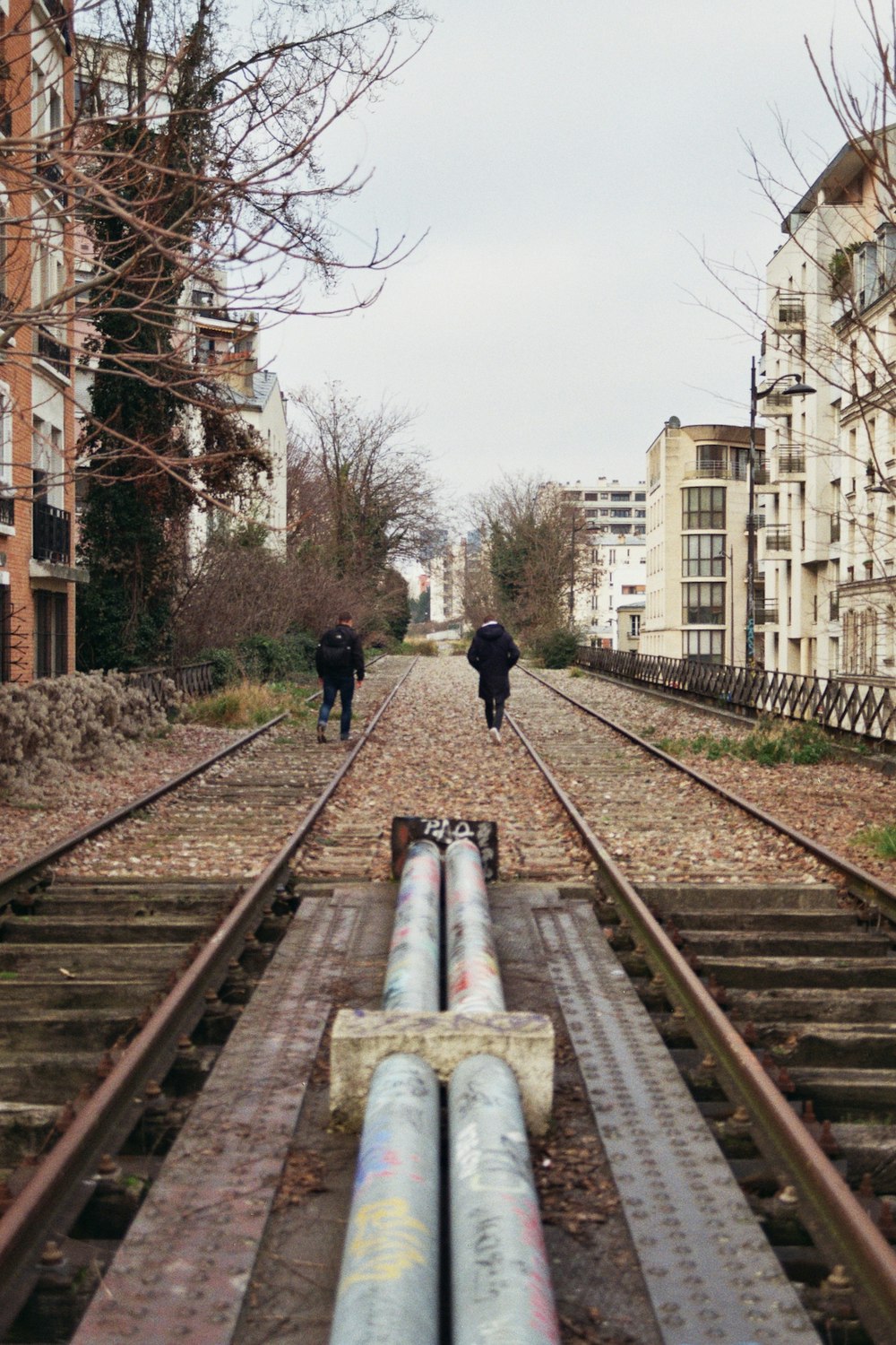 a couple of people walking down a train track