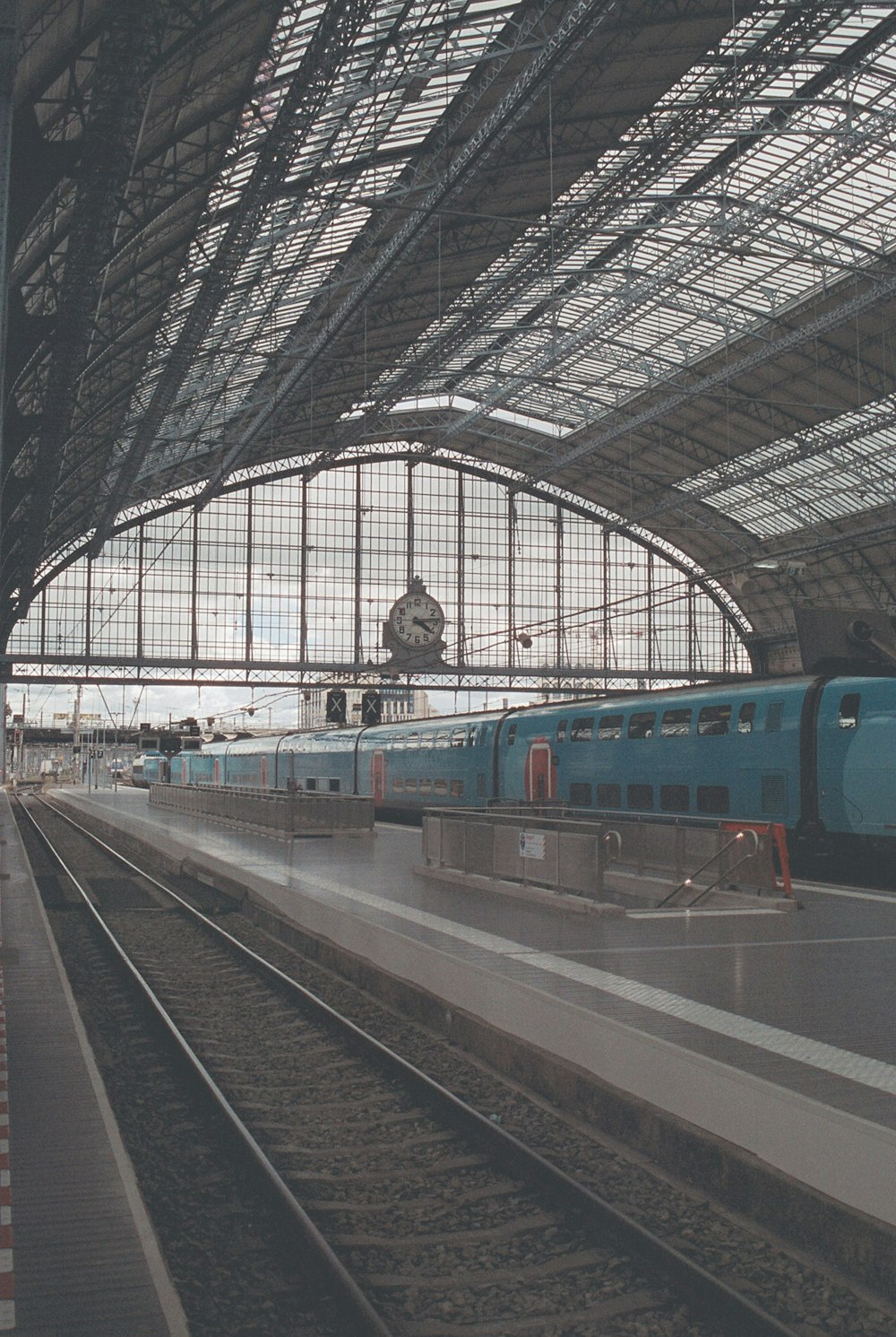 a blue train traveling down train tracks next to a train station