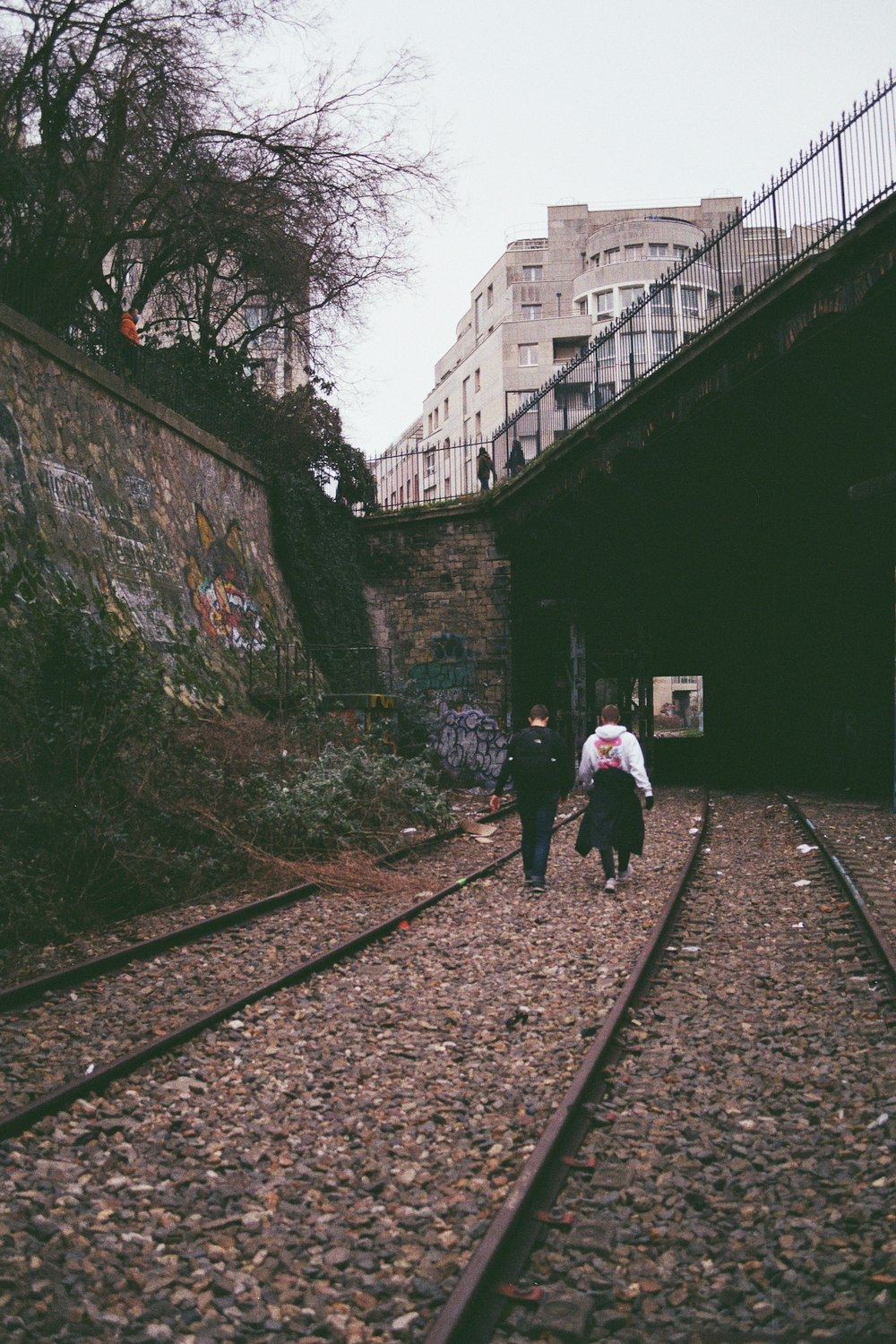 a couple of people walking down a train track