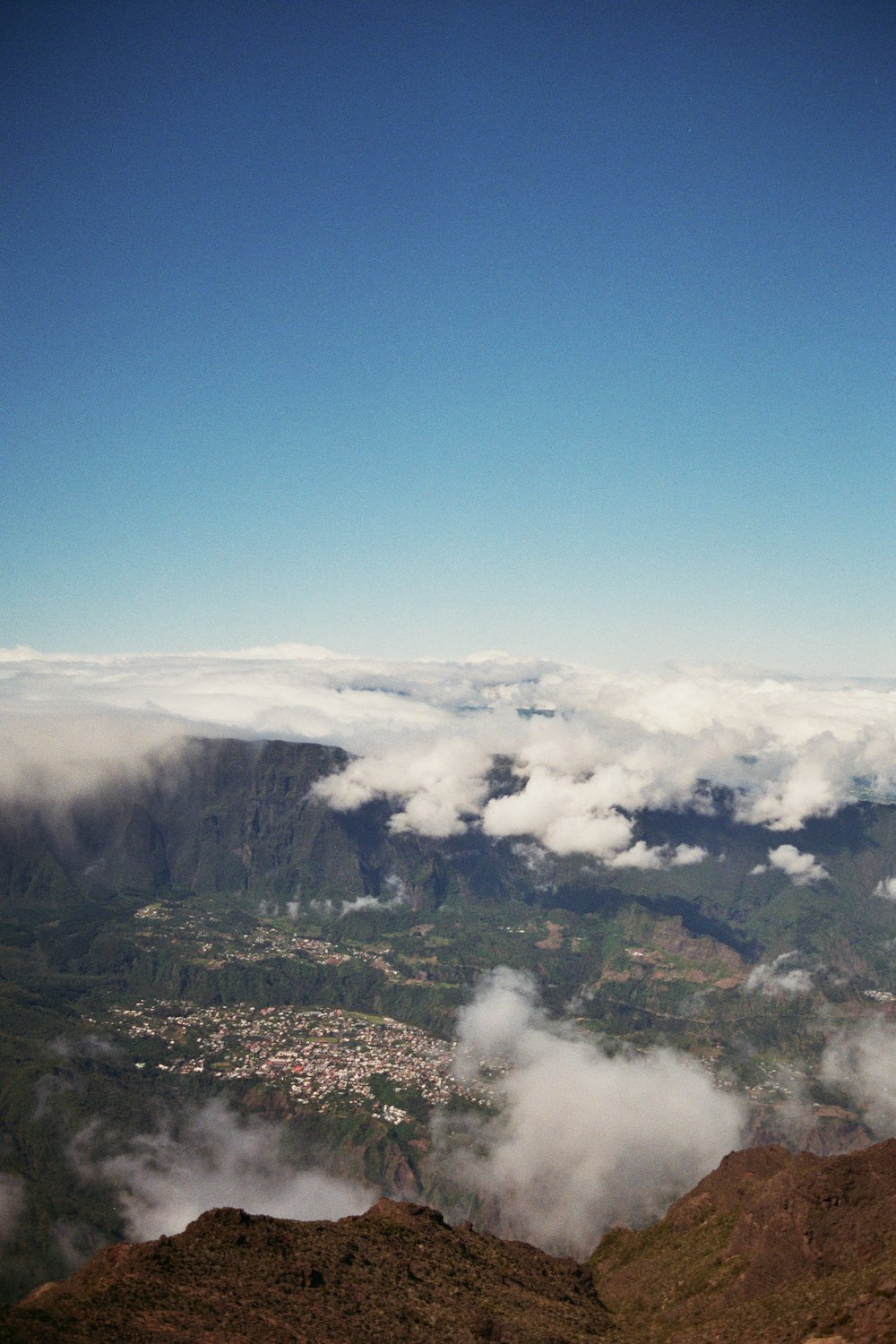 a man standing on top of a mountain next to a lush green hillside