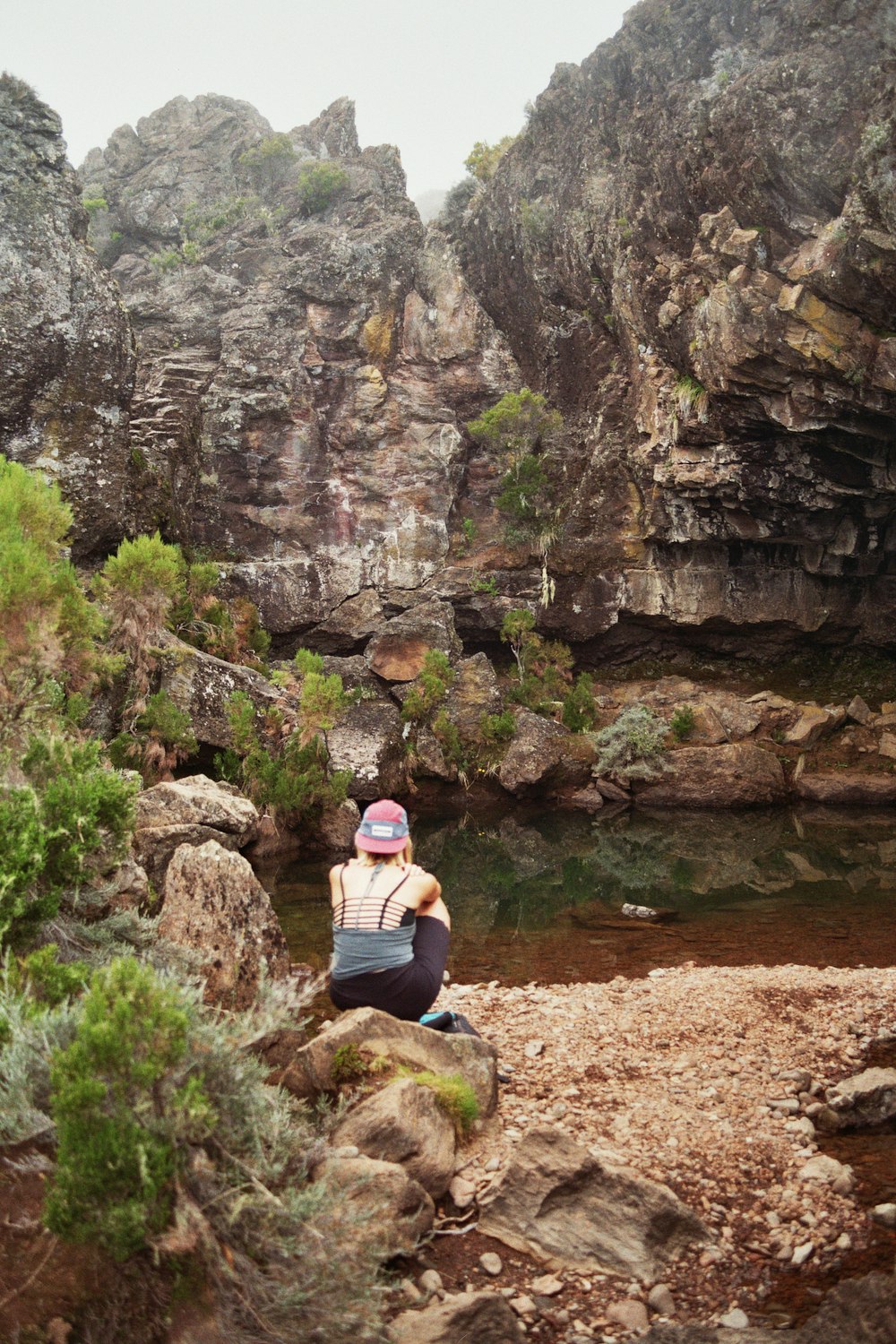 a person sitting on a rock near a body of water