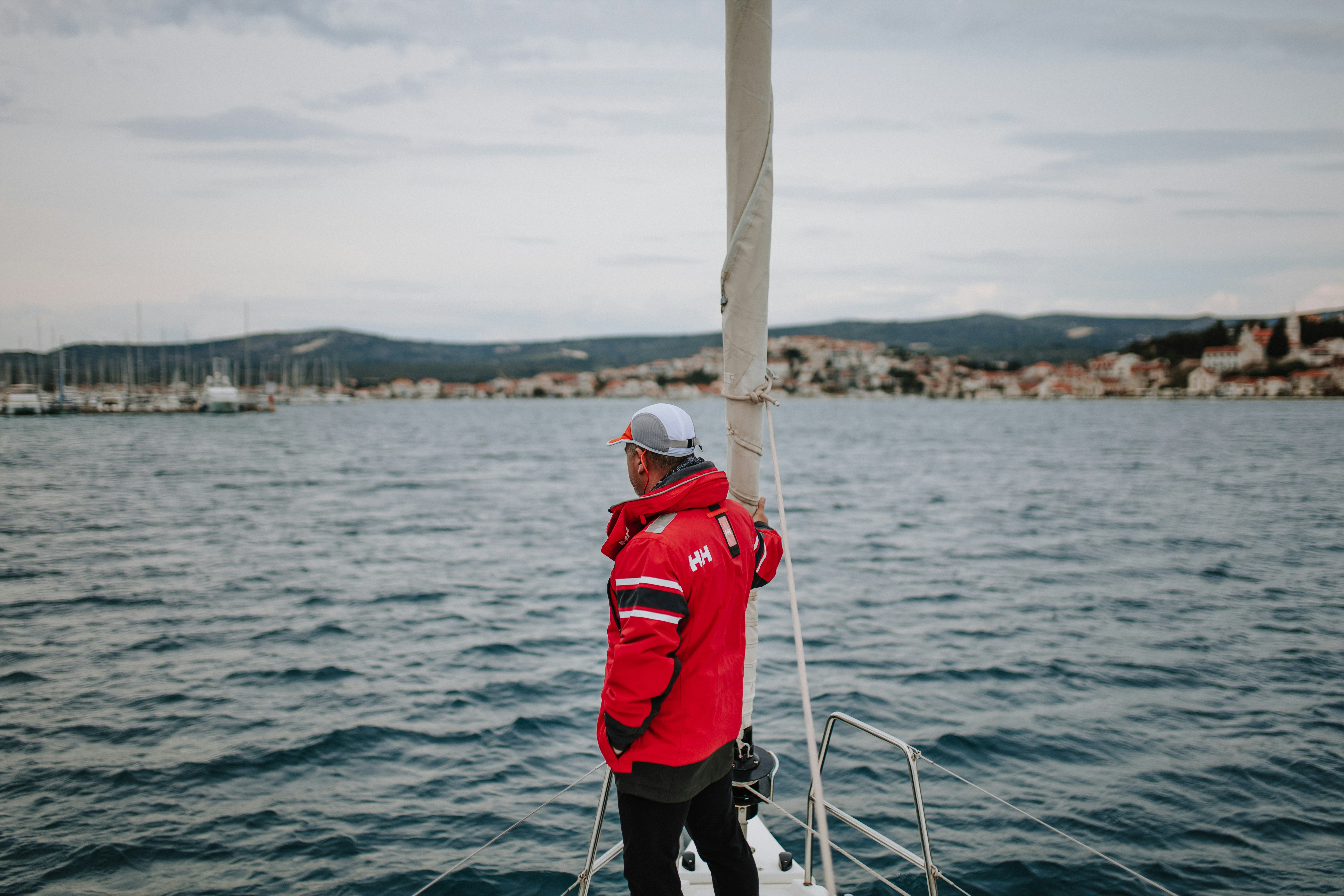 a man in a red jacket standing on a boat