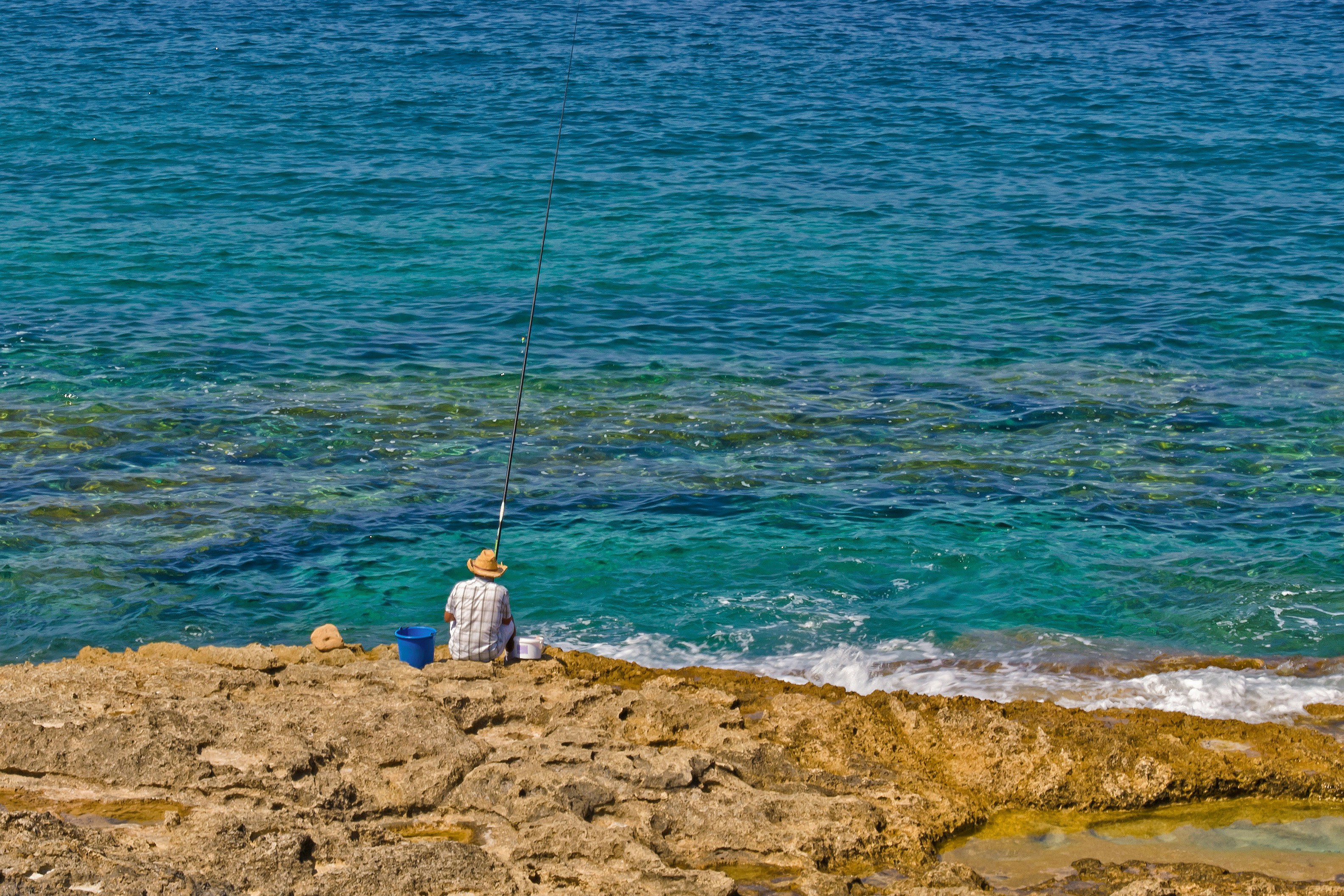 a man sitting on top of a rock next to the ocean