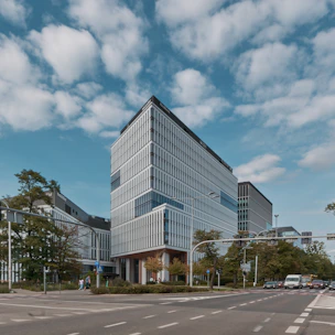 Modern office building with glass facade and busy street view.