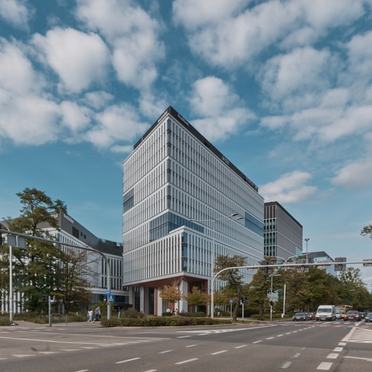 A modern office building with a city skyline in the background during daylight.