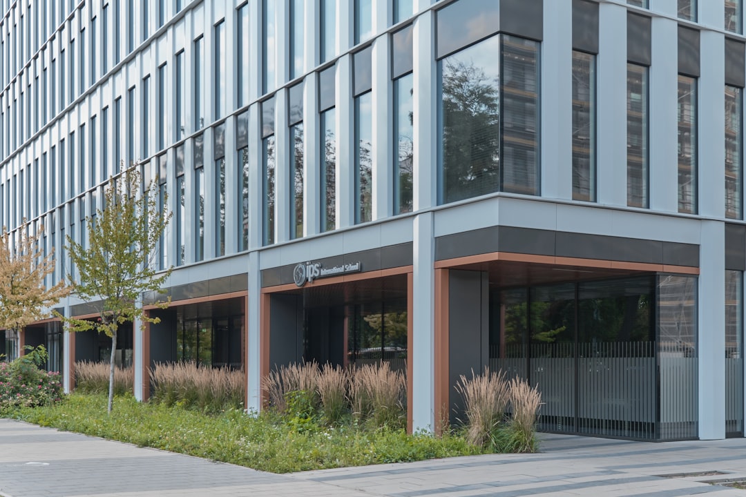 a tall building with lots of windows next to a sidewalk, Modern office buildings Centrum Południe in Wrocław for Skanska by APA Wojciechowski