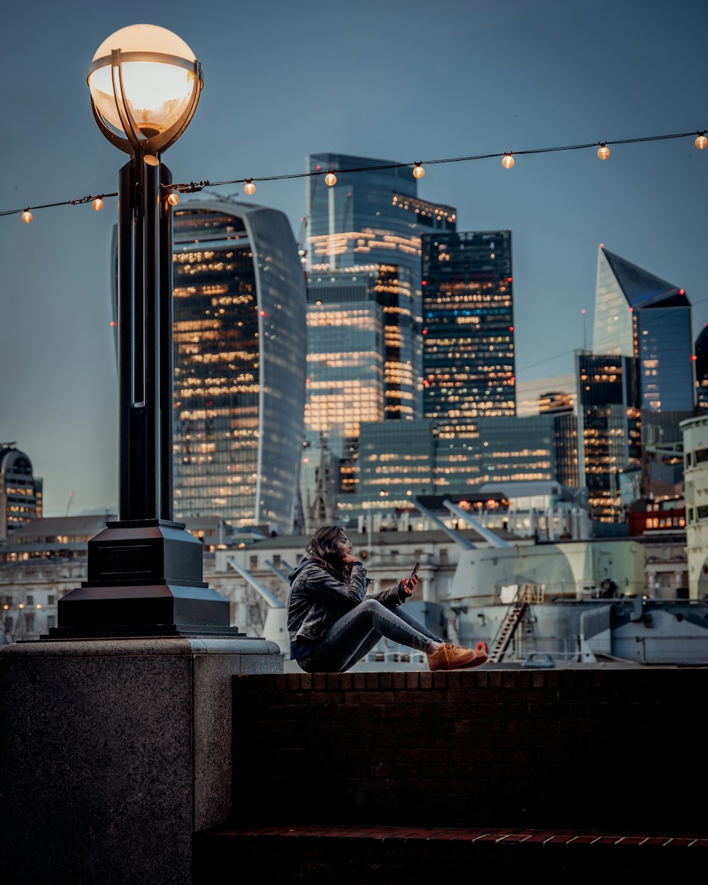 a man sitting on a ledge looking at his cell phone