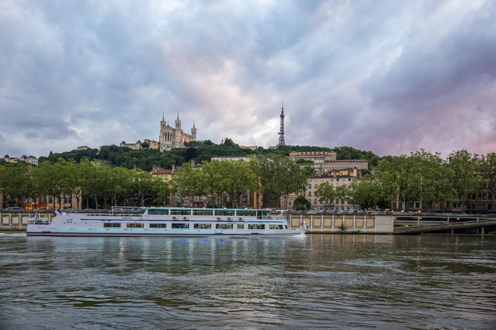 a large boat floating on top of a river under a cloudy sky