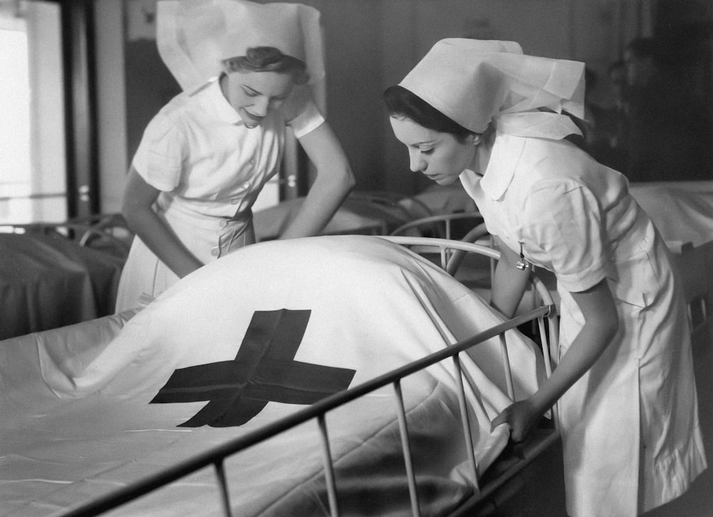 a couple of nurses standing over a bed