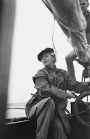 A student learning to steer a modern sailboat under the guidance of an experienced captain.