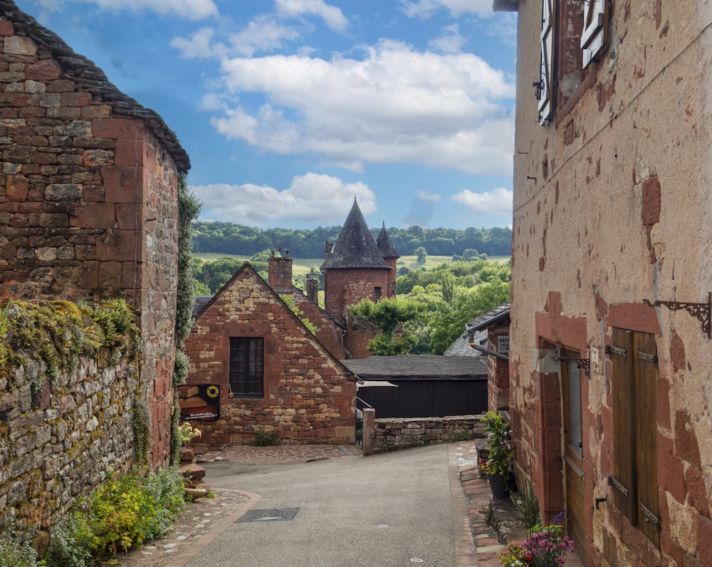 an alley way with a stone building and a clock tower in the background