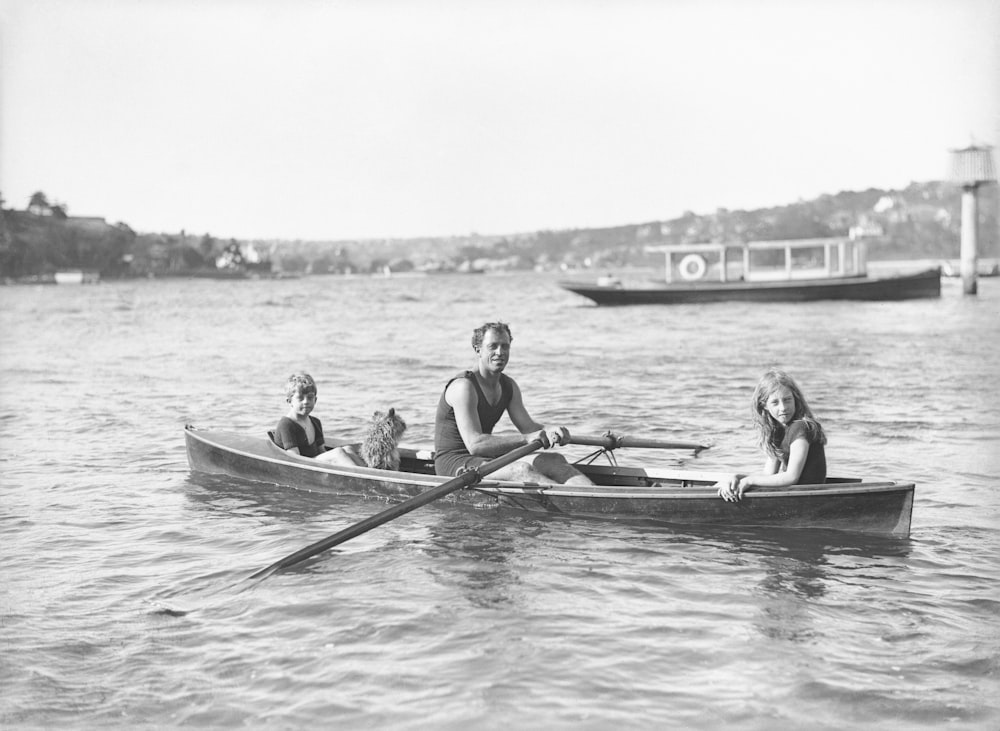 a black and white photo of three people in a canoe