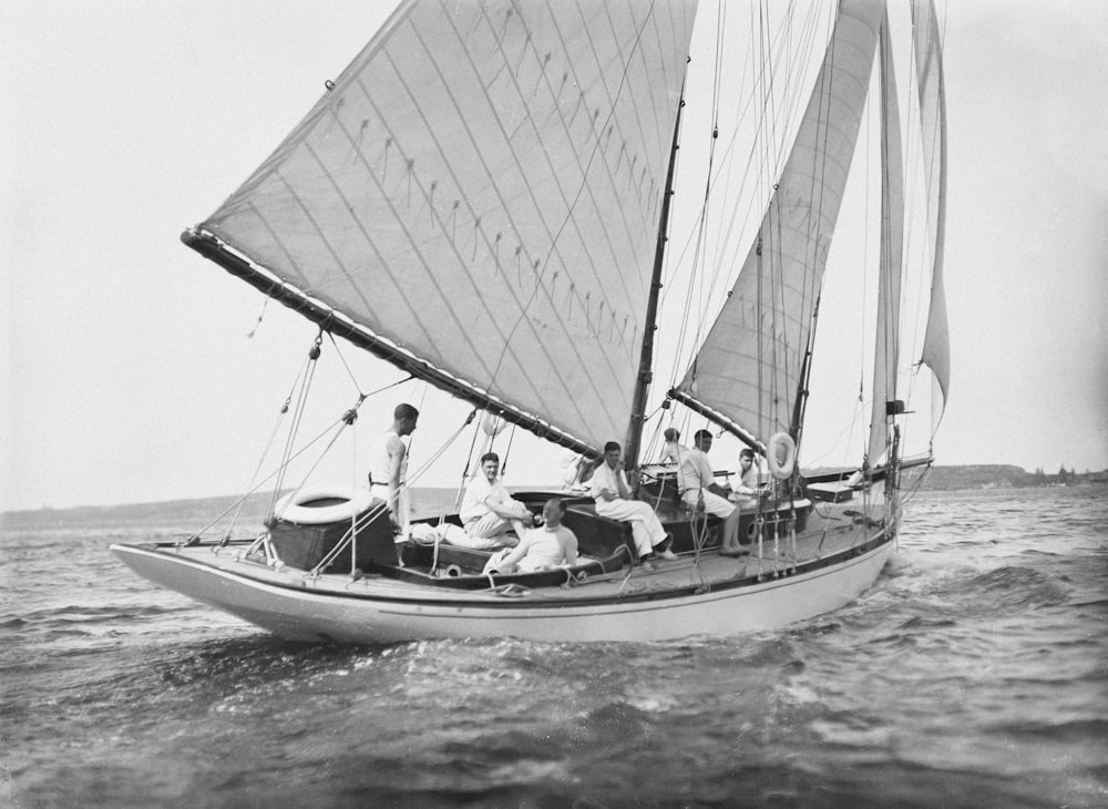 a black and white photo of people on a sailboat