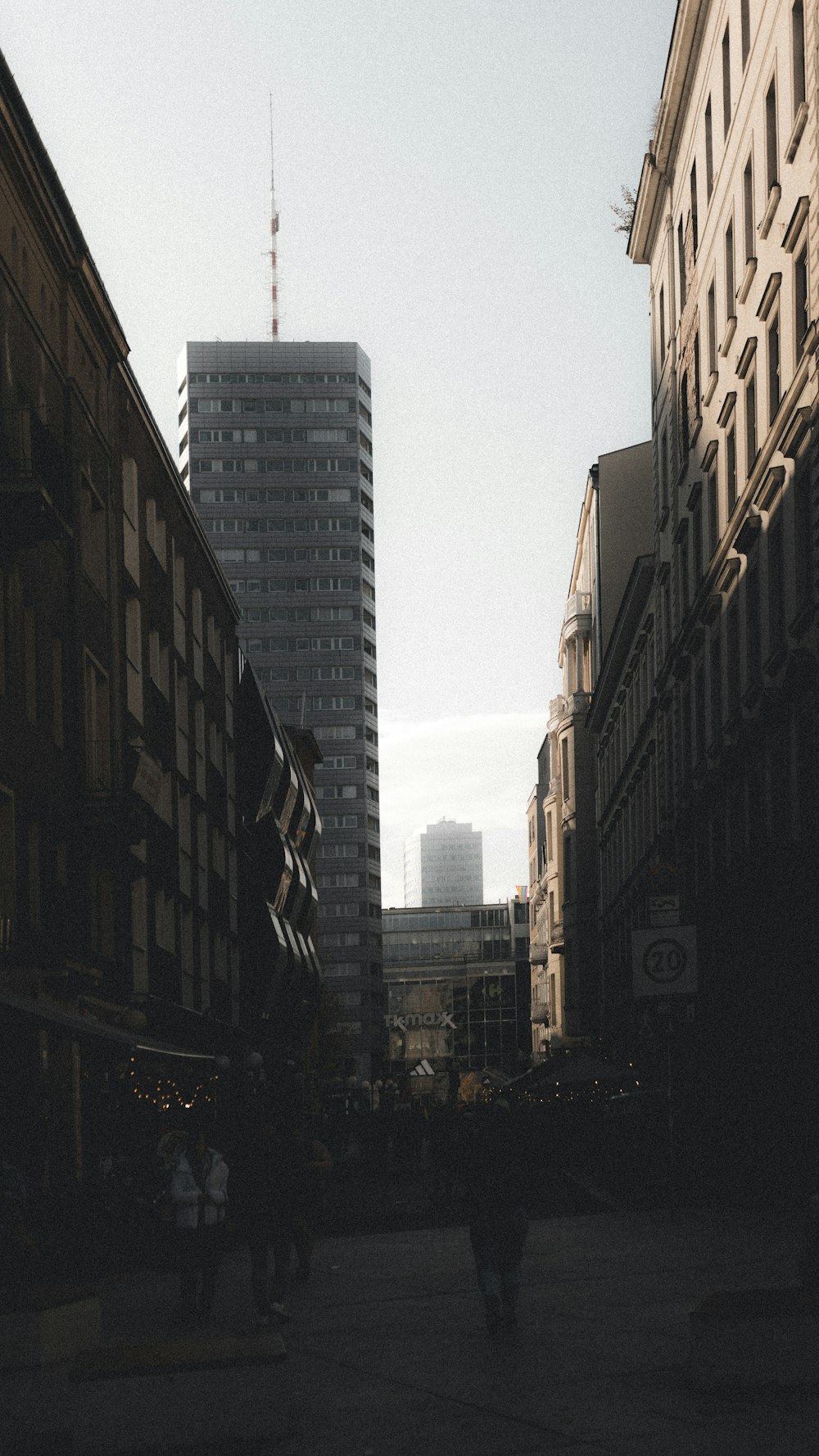 a person walking down a street next to tall buildings