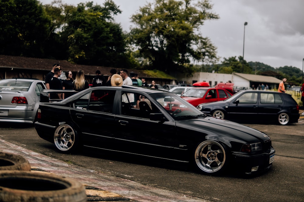 a black car parked in a parking lot next to other cars