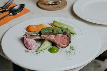 A beautifully arranged platter featuring roasted lamb surrounded by fresh vegetables and herbs.