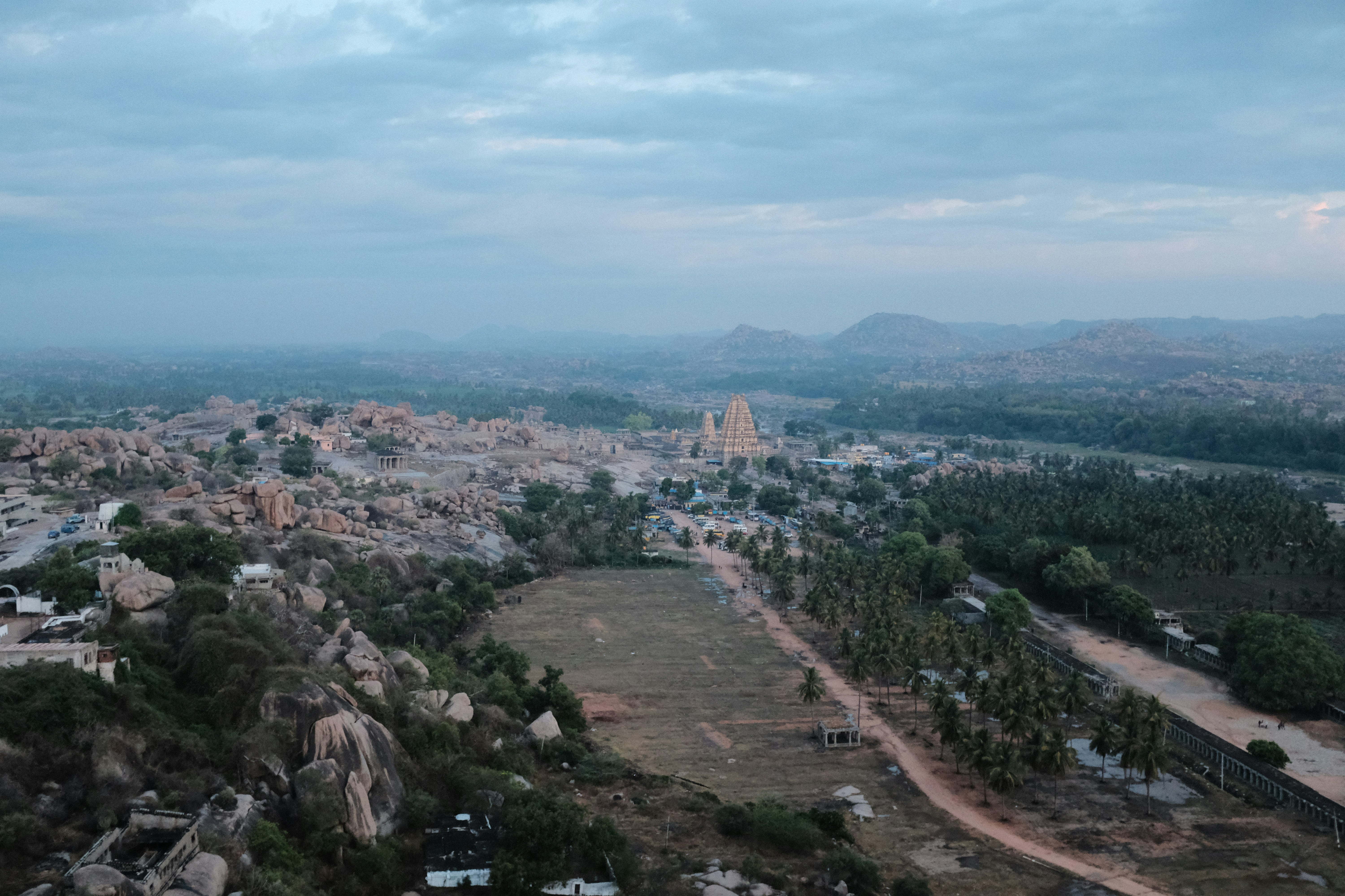Ancient stone temple ruins of Hampi with boulders and palm trees in golden afternoon light