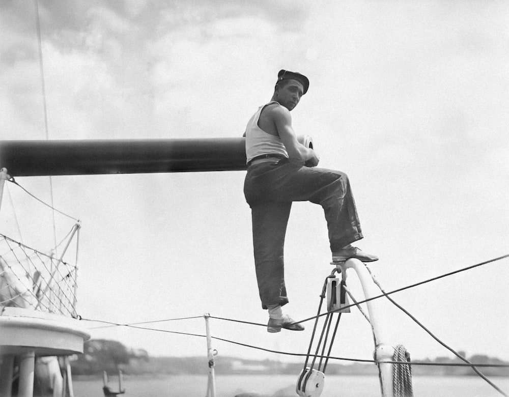 a man is sitting on a pole on a boat