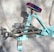 A turquoise exercise machine with metallic handles and a padded seat in contrasting colors. The design appears sturdy with a combination of steel and cushioned parts, designed for workouts. The background is a neutral fabric backdrop, providing a simple yet effective contrast to the machine.