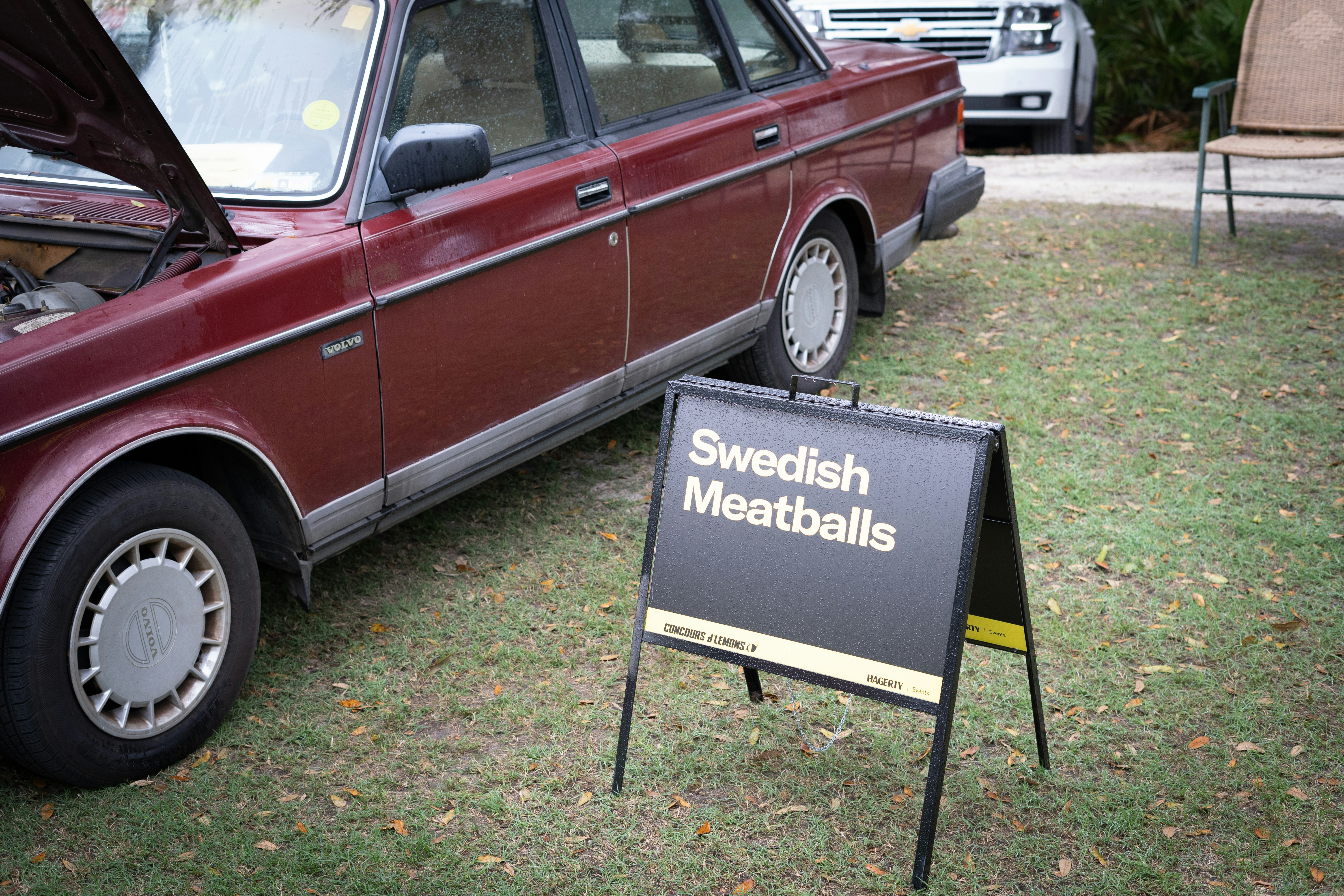a red car is parked next to a sign that says swedish meatballs, 