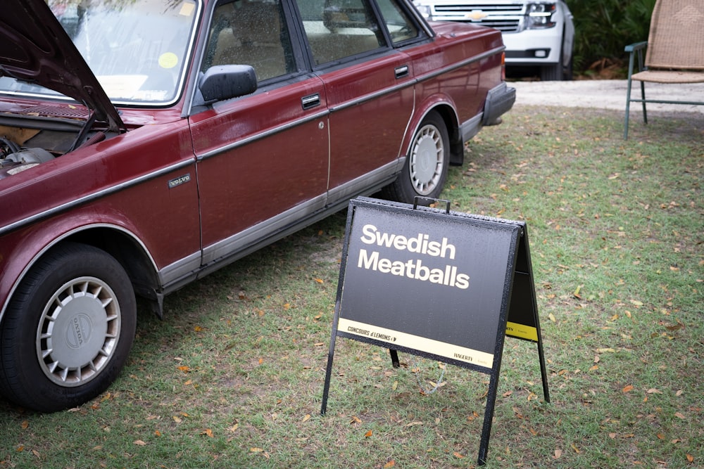 a red car is parked next to a sign that says swedish meatballs