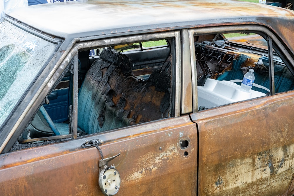 a rusted out car with a broken windshield
