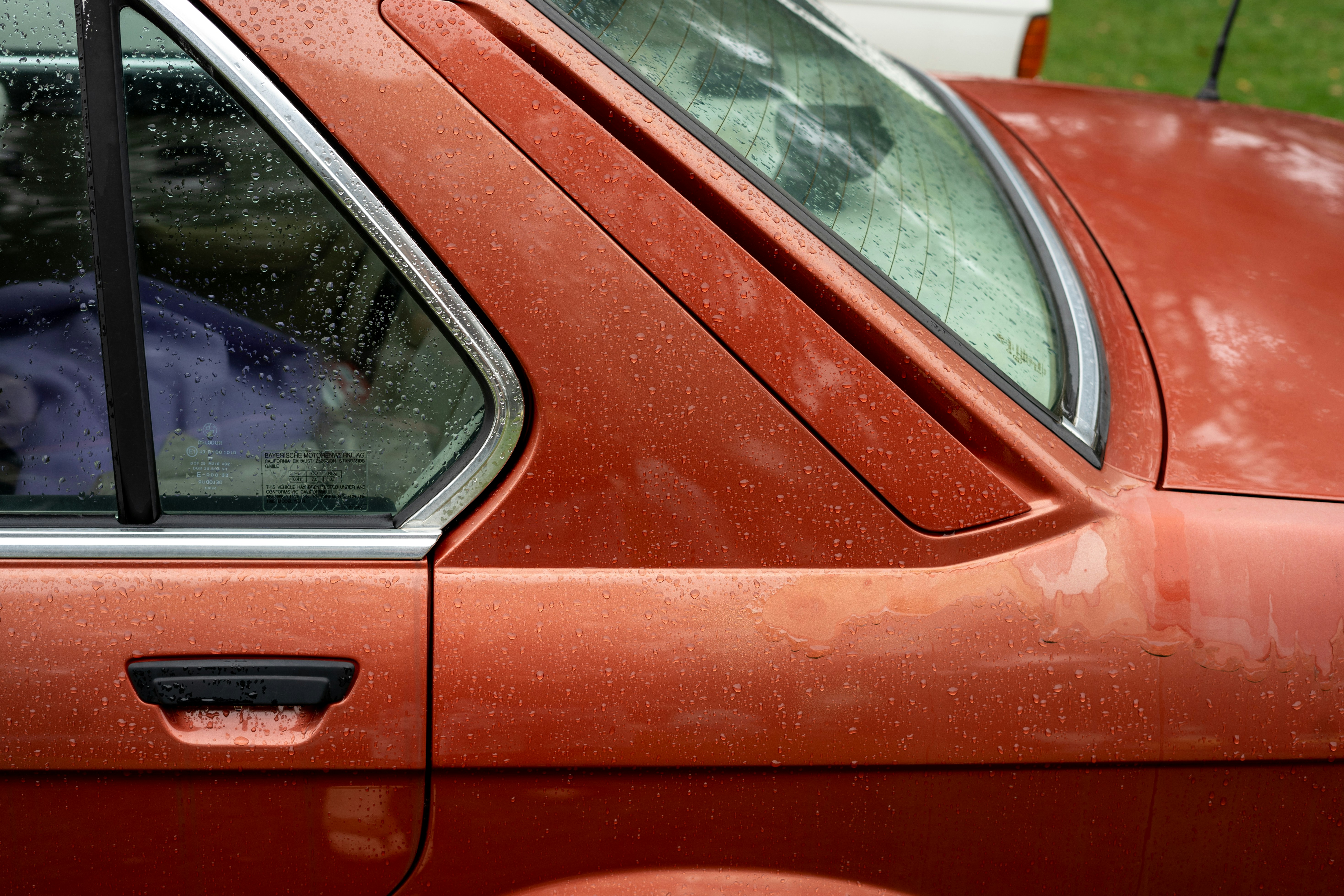 a dog sitting in the drivers seat of a red car, 
