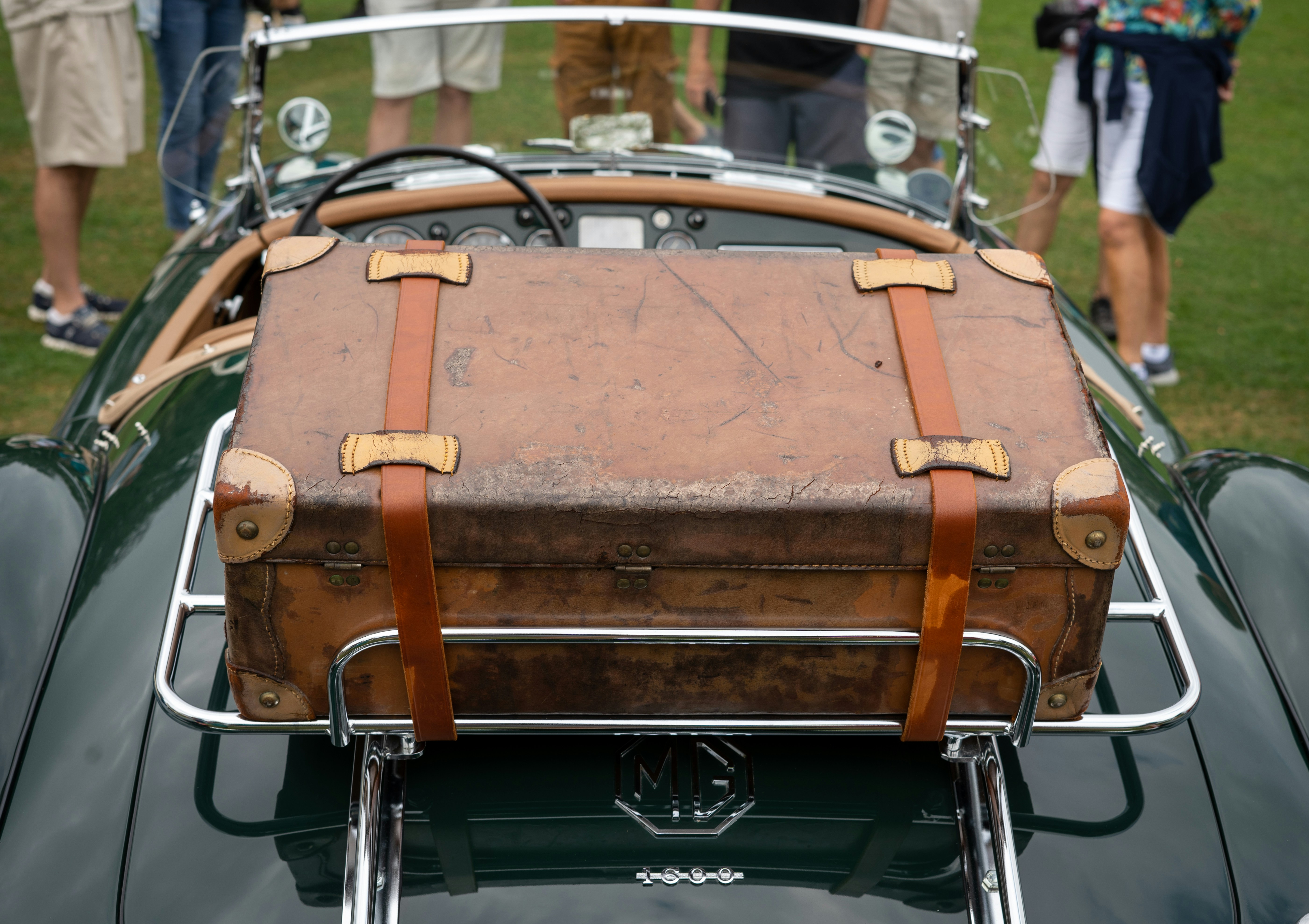 a brown suitcase sitting on top of a green car, 