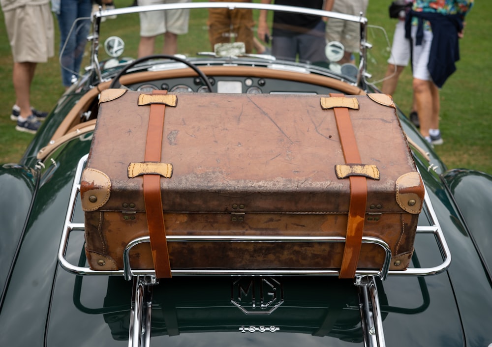 a brown suitcase sitting on top of a green car