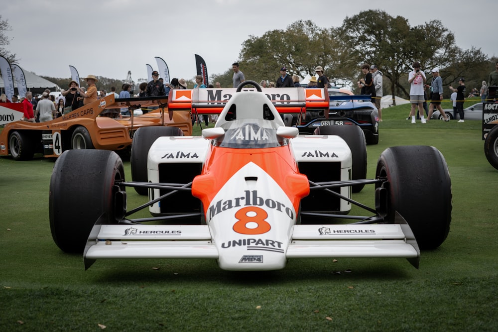 Un auto de carreras naranja y blanco en exhibición en una exhibición de autos