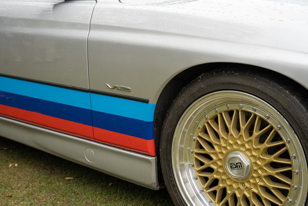 a silver car with a blue, red, and blue stripe painted on the side