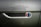 Raindrops cover the metallic surface of a vehicle, focusing on an emblem that reads 'Smit Vehicle Engineering' with a multicolored design. The background is slightly blurred, highlighting the text and colors.
