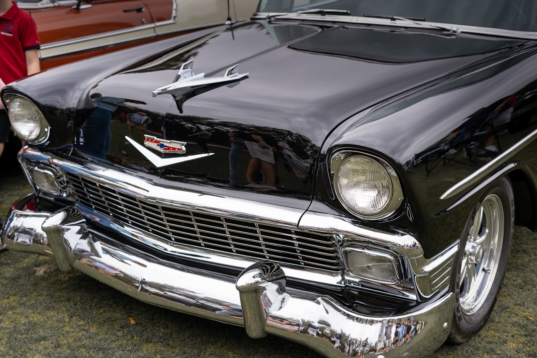a black classic car parked next to a red car,