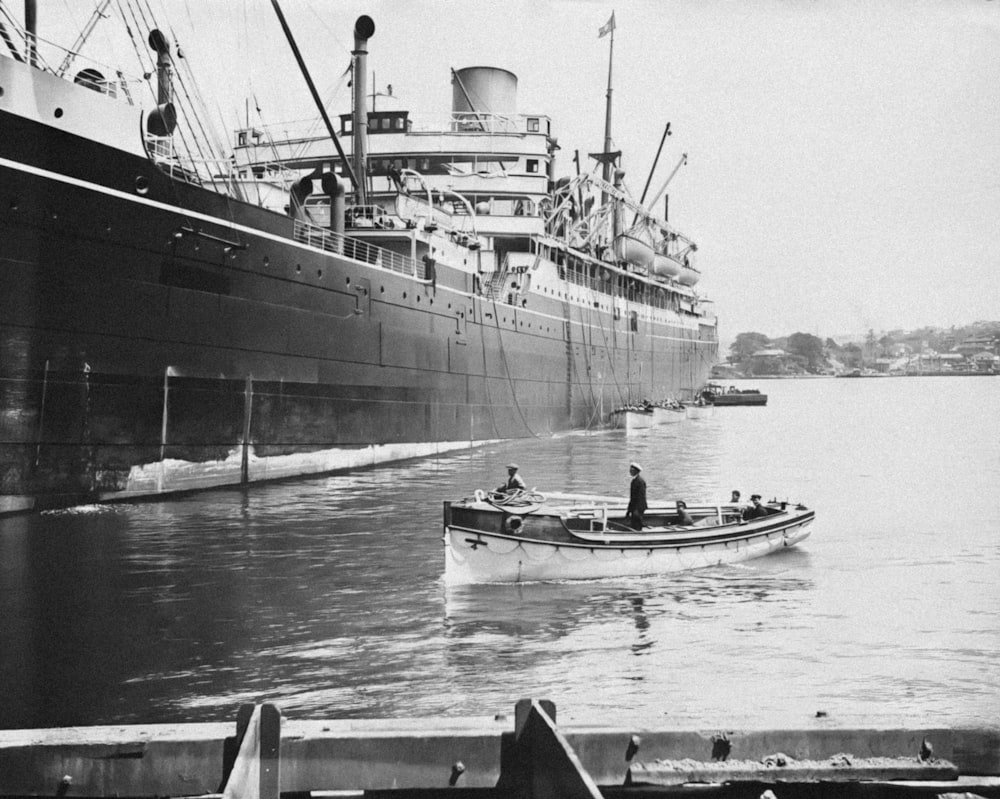 a small boat in the water next to a large ship