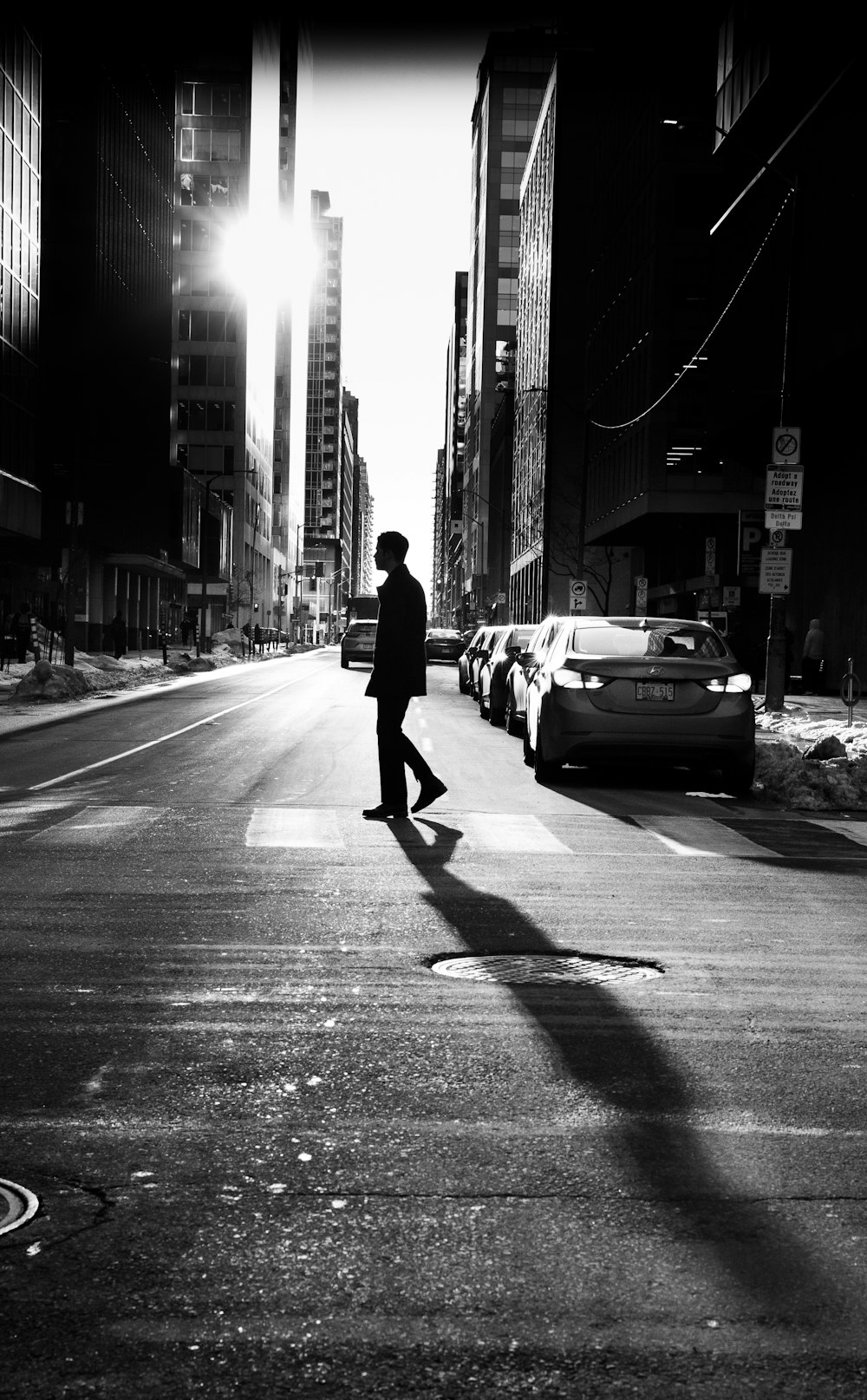 a man walking across a street next to tall buildings