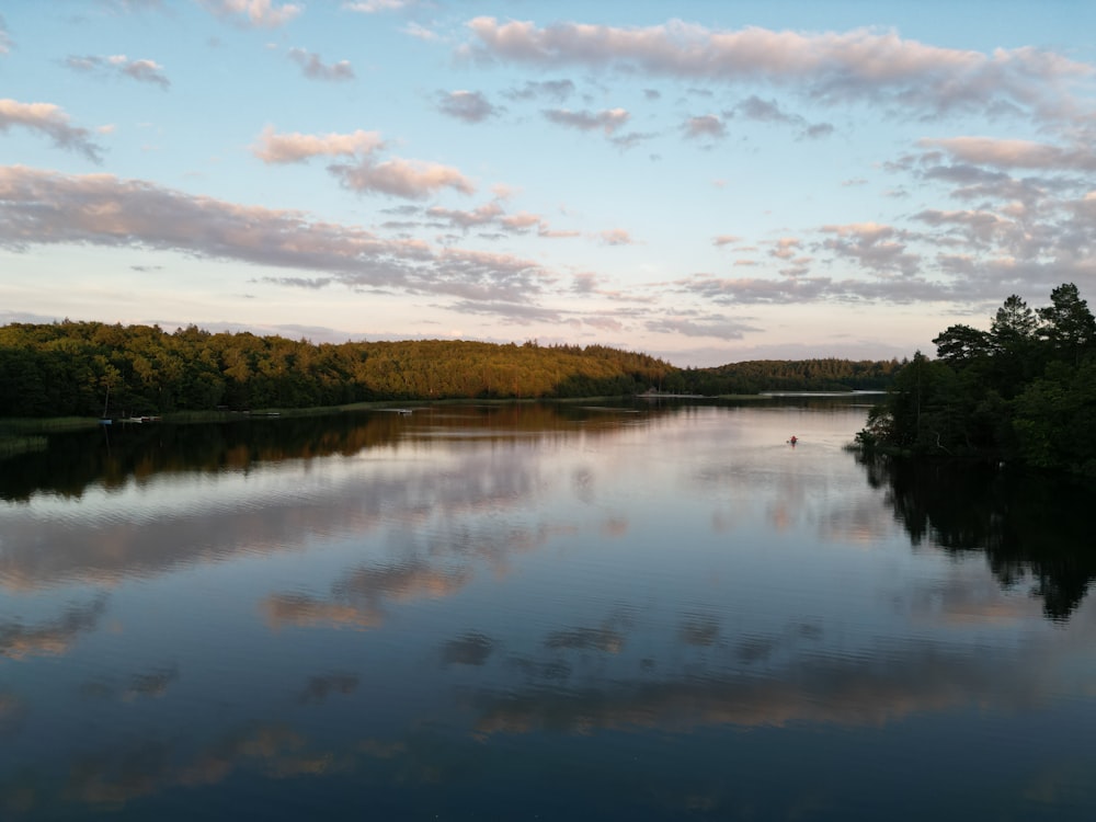 a body of water surrounded by trees and clouds