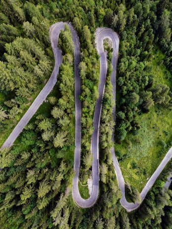 High-resolution photo taken by drone showing a winding mountain road surrounded by lush forest.