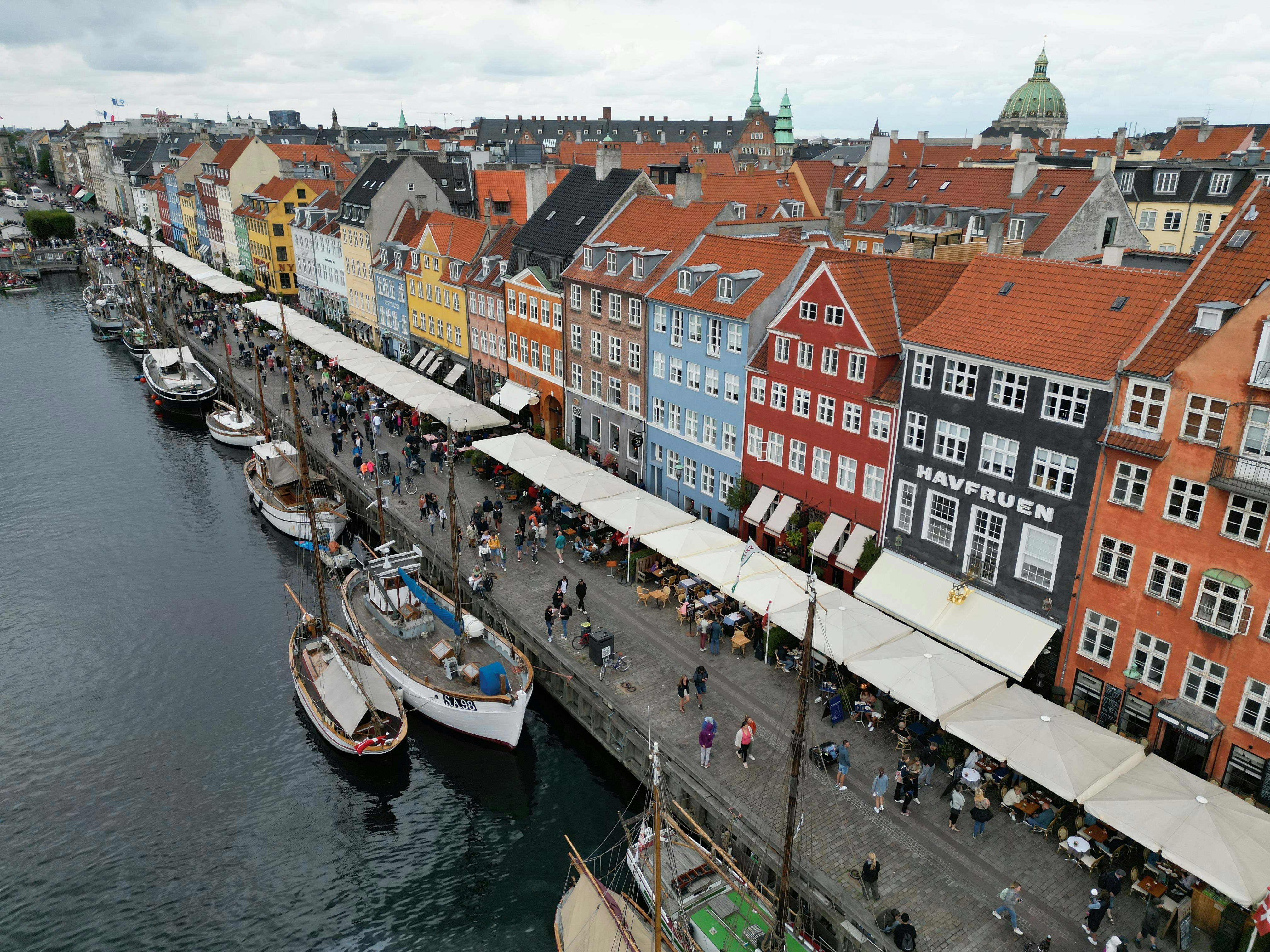 a group of people walking down a street next to a body of water