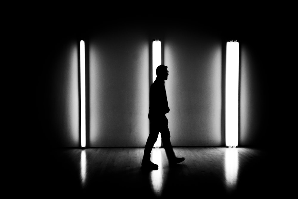 a man walking through a dark room next to a wall
