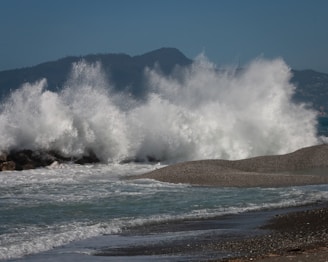 a large wave crashes into the shore of a beach