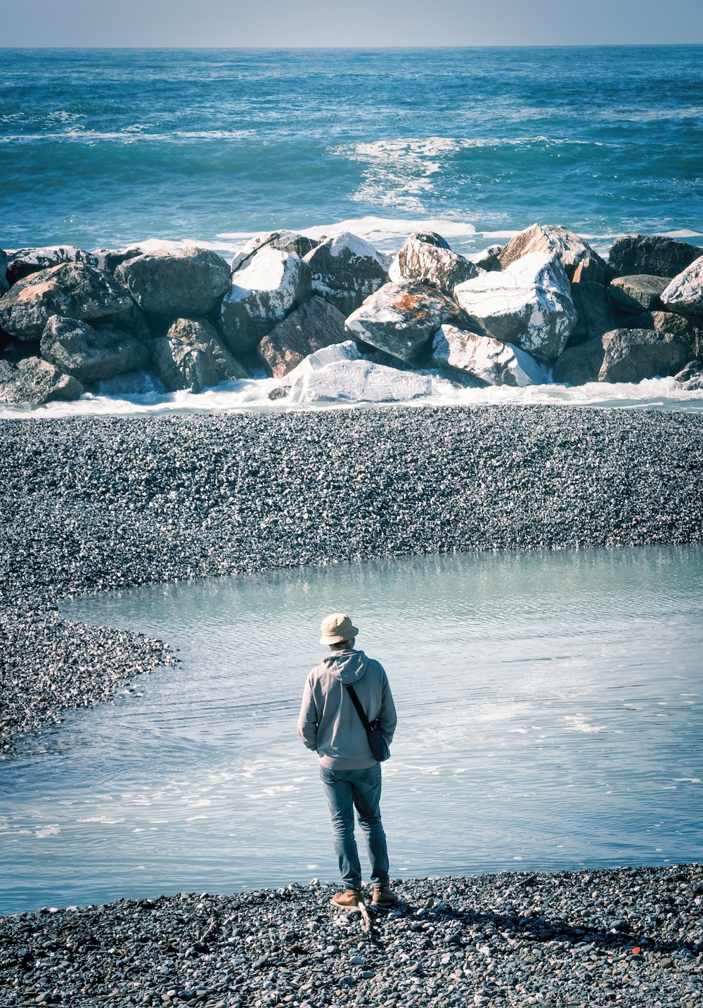 a man standing on a beach next to a body of water