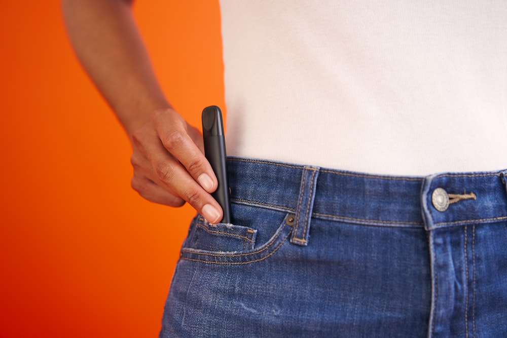 a person holding a cell phone in their pocket
