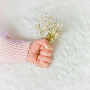 Bright teething ring shaped like a flower held by tiny baby hands