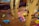 A playful indoor playground area covered in a brown, sand-like material with scattered colorful plastic toys, including toy trucks, containers, and building blocks. Large tree-like structures with a cartoonish design are situated throughout the scene, giving it a whimsical forest theme.