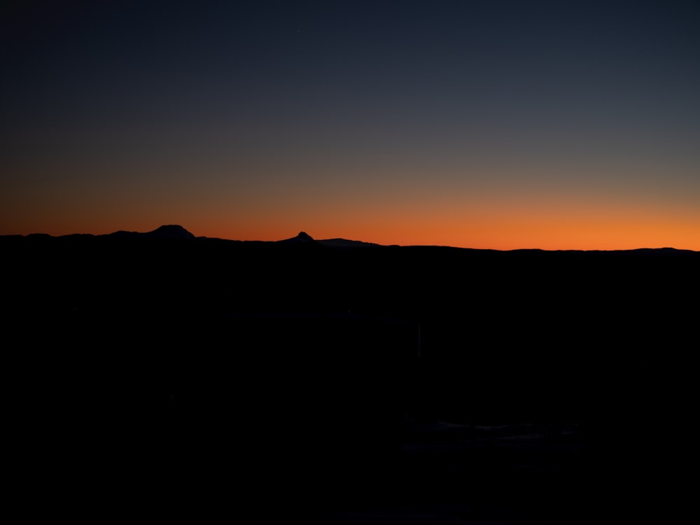 the sun is setting over a mountain range