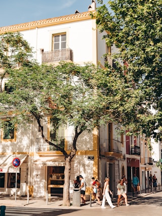 a group of people walking down a street next to a tall building