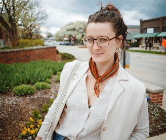 a woman wearing glasses and a white jacket