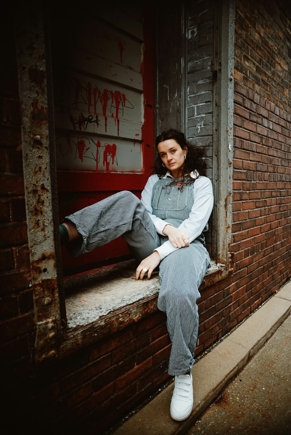 a woman sitting on a window sill in front of a brick building